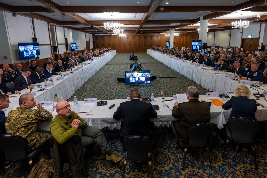 Defense Secretary  Lloyd J. Austin III sits at the head of tables in a "U" formation with civilian and military officials.