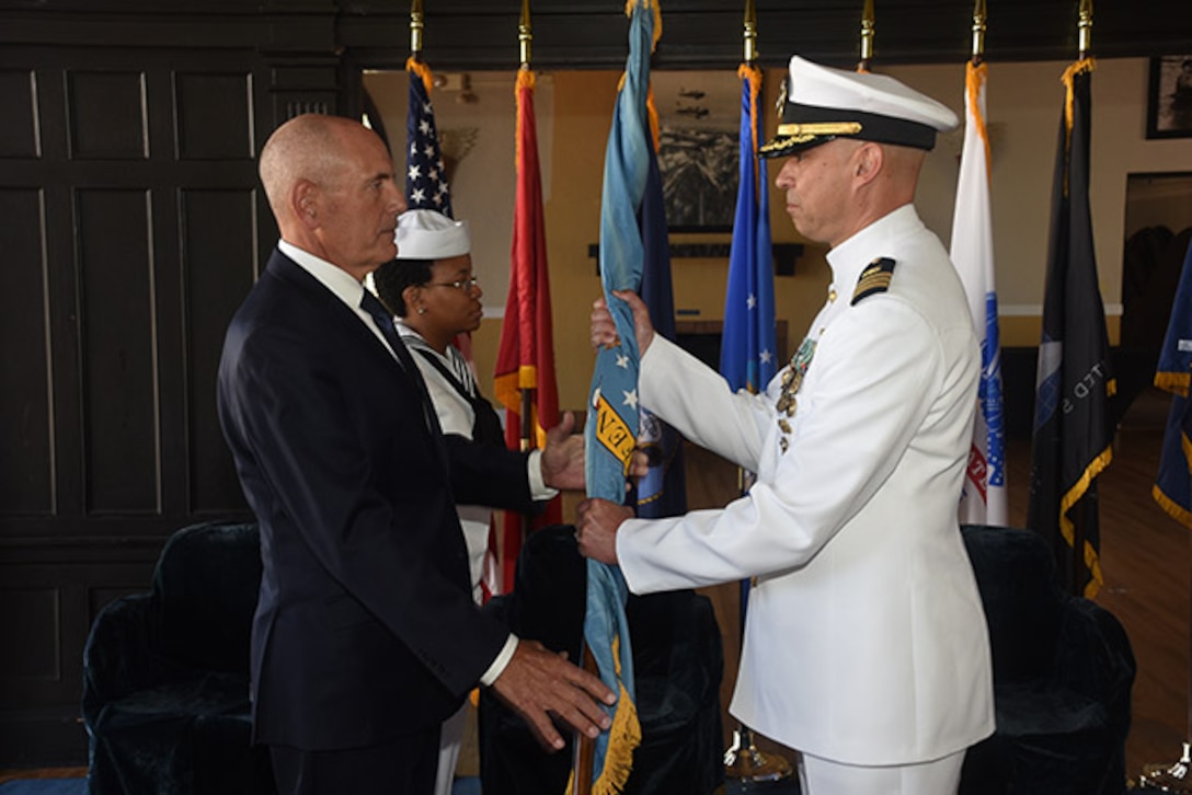 DLA Aviation Deputy Commander Charlie Lilli passes the DLA flag to Navy Commander Fred Albesa as he assumes command.