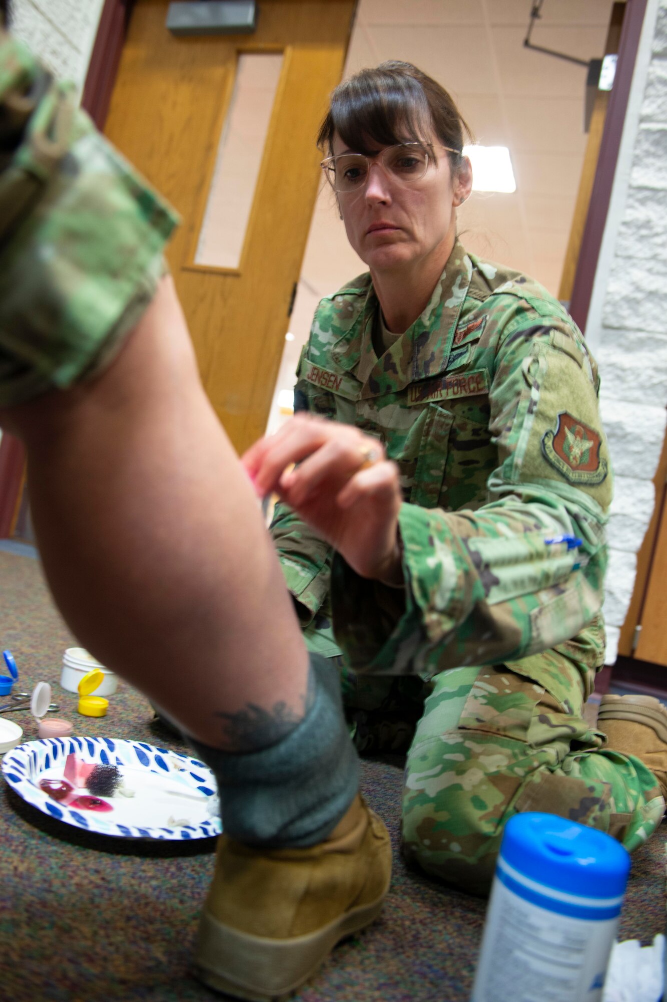 Maj. Deanna Jensen, a clinical nurse with the 934th Aeromedical Staging Squadron, touches up a simulated compound fracture on Staff Sgt. Sara Syverhus’s, 934 ASTS medical technician, leg on April 7, 2022, at Volk Field Air National Guard Base, Wis. Syverhus and other Airmen had moulage applied to them for a simulated mass casualty training exercise supporting Viking Shield. (U.S. Air Force photo by Chris Farley)