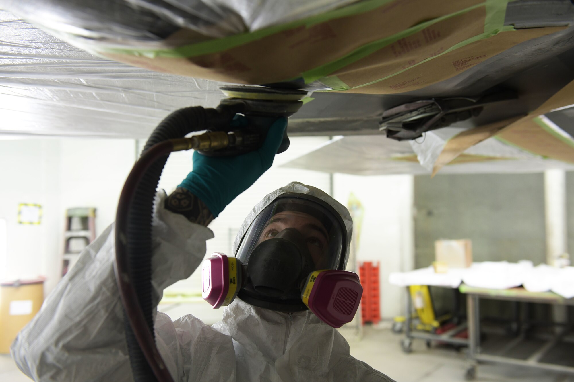 U.S. Air Force Staff Sgt. August Hoffman, 325th Maintenance Squadron low observable craftsman, sands off paint from an F-22 Raptor at Tyndall Air Force Base, Florida, March 28, 2022.