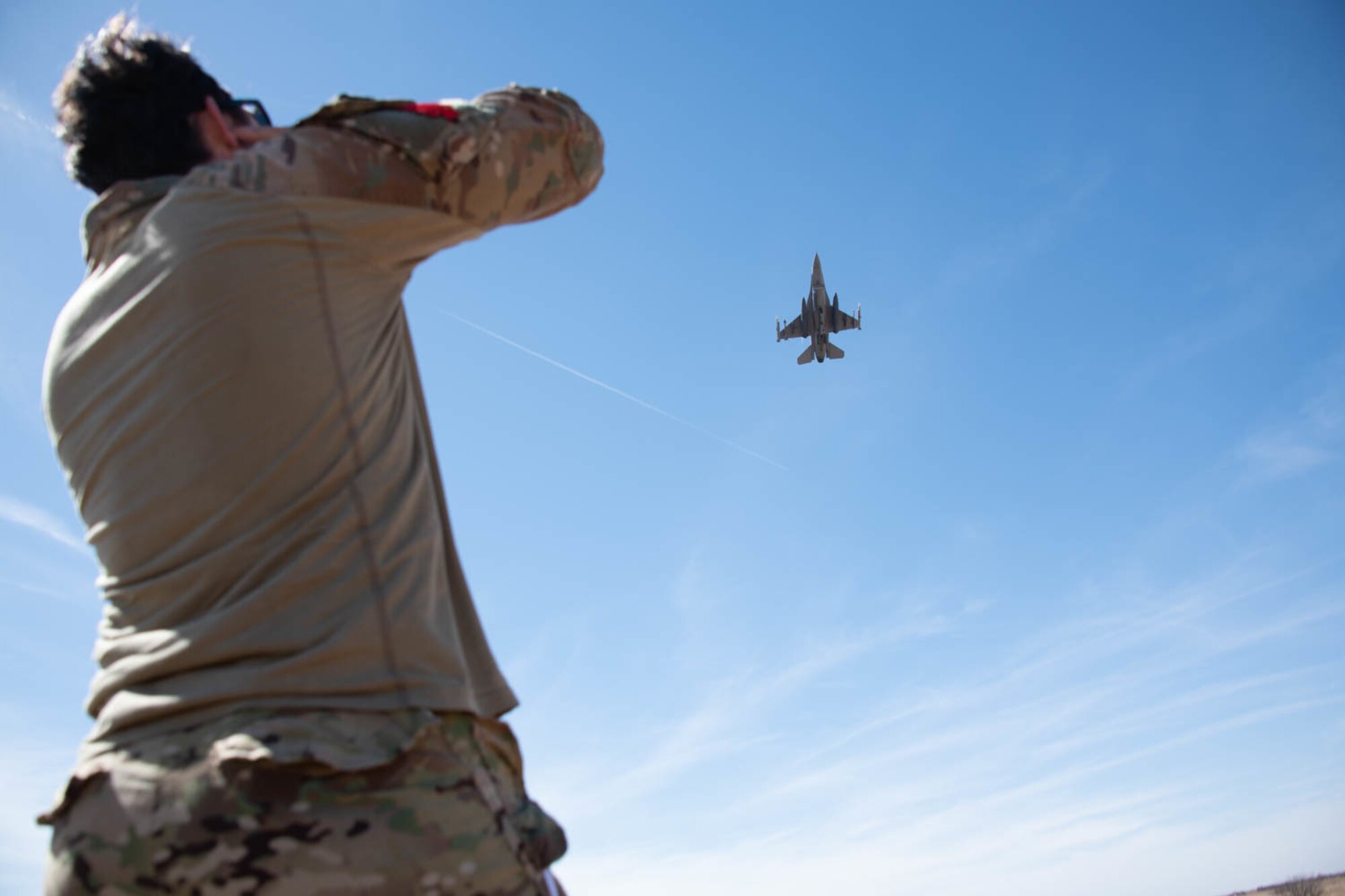 man watches plane fly overhead