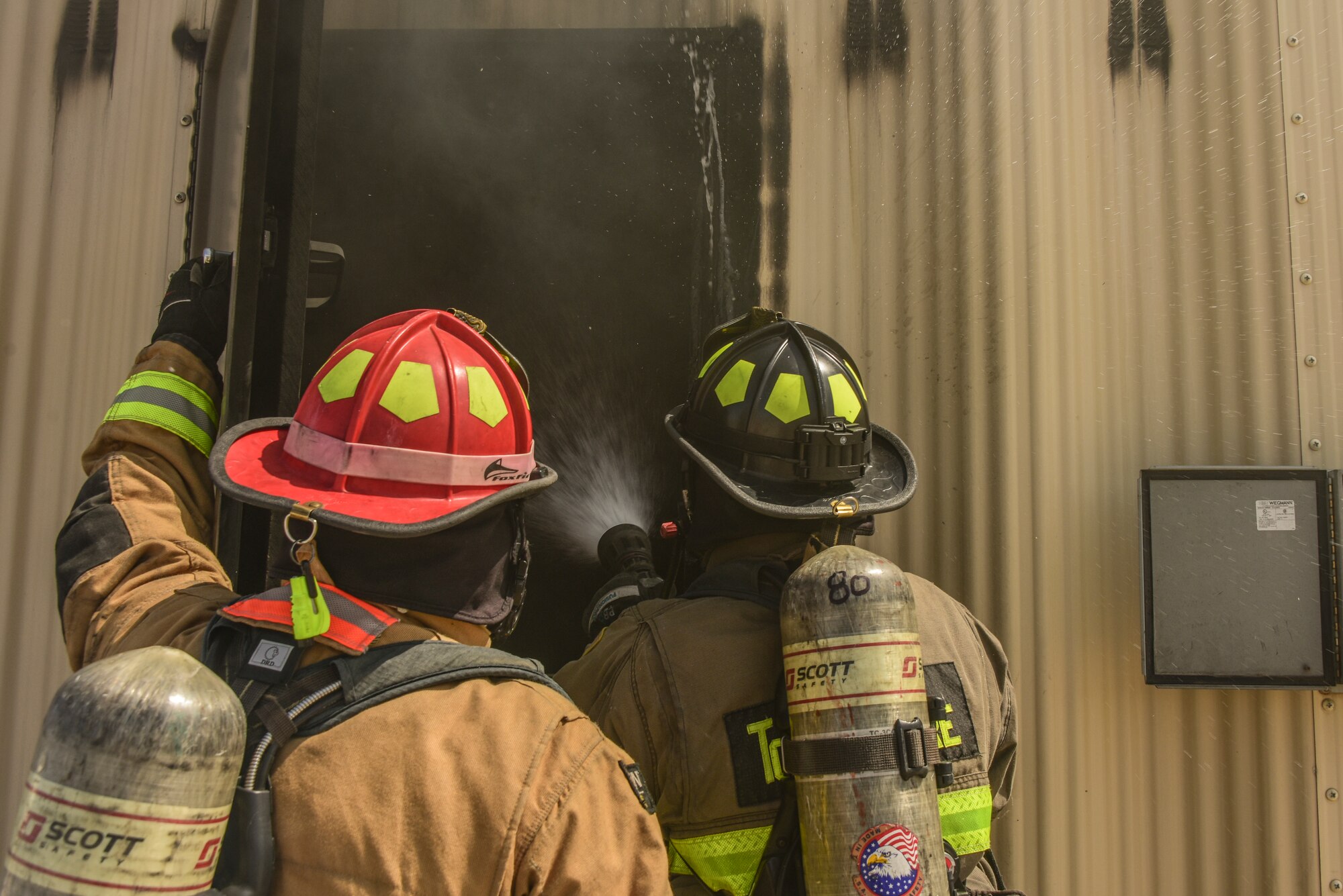 A photo of two firefighters spraying fire.