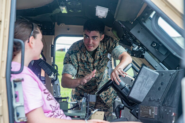 U.S. Marine Corps Cpl. Michael Litton, a motor transportation operator with 3rd Transportation Battalion, 3rd Marine Logistics Group, explains the functions of a Joint Light Tactical Vehicle during the Headquarters and Support Battalion Family Day event on Camp Foster, Okinawa, Japan, on April 22, 2022. Family Day allowed service members to engage in activities with their children, allowing them to view military vehicles, participate in a mock combat fitness test, and learn professional training from the Marine Corps Martial Arts Program and the Marksmanship Training Unit. (U.S. Marine Corps photo by Cpl. Alex Fairchild)
