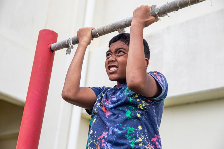 Families of service members conduct pull-ups during the Headquarters and Support Battalion Family Day event on Camp Foster, Okinawa, Japan, on April 22, 2022. Family Day allowed service members to engage in activities with their children, allowing them to view military vehicles, participate in a mock combat fitness test, and learn professional training from the Marine Corps Martial Arts Program and the Marksmanship Training Unit. (U.S. Marine Corps photo by Cpl. Alex Fairchild)