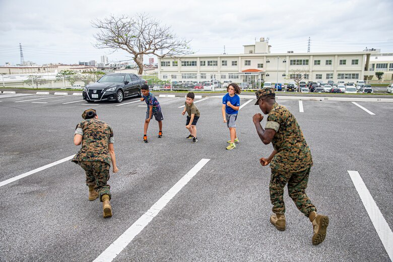Families of service members learn martial arts techniques during the Headquarters and Support Battalion Family Day event on Camp Foster, Okinawa, Japan, on April 22, 2022. Family Day allowed service members to engage in activities with their children, allowing them to view military vehicles, participate in a mock combat fitness test, and learn professional training from the Marine Corps Martial Arts Program and the Marksmanship Training Unit. (U.S. Marine Corps photo by Cpl. Alex Fairchild)