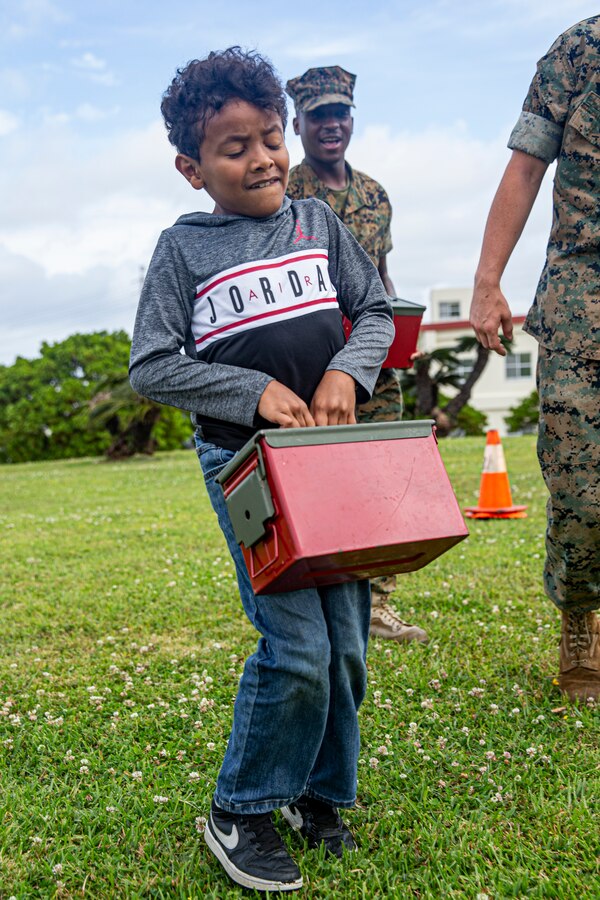 Service members and their families participate in a mock combat fitness test during the Headquarters and Support Battalion Family Day event on Camp Foster, Okinawa, Japan, on April 22, 2022. Family Day allowed service members to engage in activities with their children, allowing them to view military vehicles, participate in a mock combat fitness test, and learn professional training from the Marine Corps Martial Arts Program and the Marksmanship Training Unit. (U.S. Marine Corps photo by Cpl. Alex Fairchild)