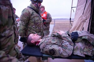 Cpt. Kyle Wall, a clinical nurse with the 934th Aeromedical Staging Squadron, is carried by 934 ASTS members on a stretcher during a mass casualty training exercise on April 7, 2022, at Volk Field Air National Guard Base, Wis. Wall and other Airmen had moulage applied to them for a simulated mass casualty training exercise supporting Viking Shield. (U.S. Air Force photo by Chris Farley)