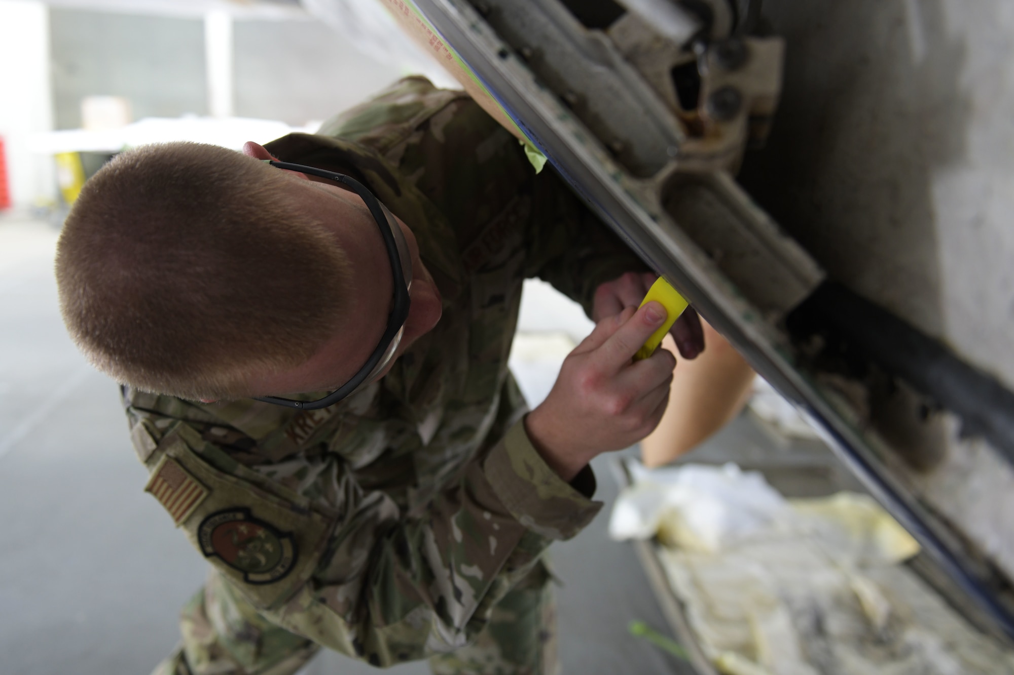 U.S. Air Force Senior Airman William Kretzer, 325th Maintenance Squadron low observable journeyman, scrapes paint from an F-22 Raptor at Tyndall Air Force Base, Florida, March 28, 2022.