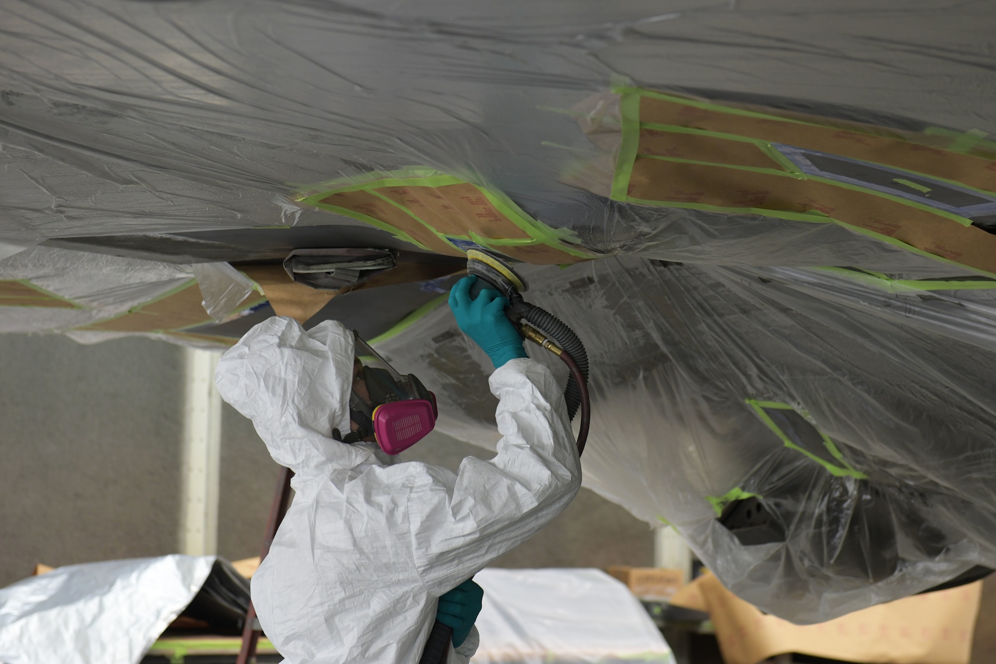 U.S. Air Force Staff Sgt. August Hoffman, 325th Maintenance Squadron low observable craftsman, sands off paint from an F-22 Raptor at Tyndall Air Force Base, Florida, March 28, 2022.