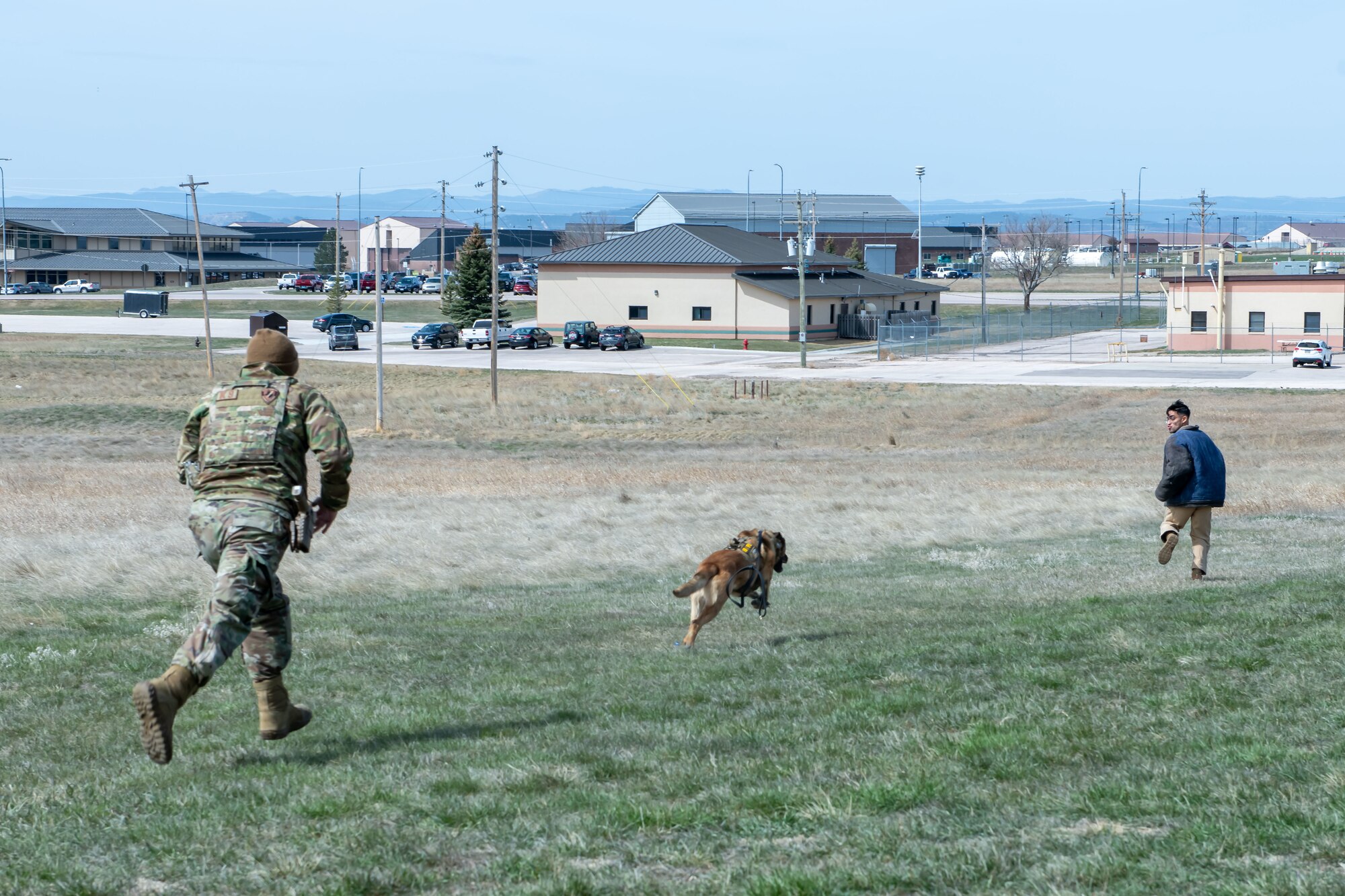 Airmen with the 28th Security Forces Squadron K-9 unit demonstrate procedures for apprehending a suspect at Ellsworth Air Force Base, S.D., April 19, 2022. Security Forces performed these procedures as an educational show for the Douglas High School Air Force Junior Reserve Officer Training Corps. (U.S. Air Force photo by Airman 1st Class Adam Olson)