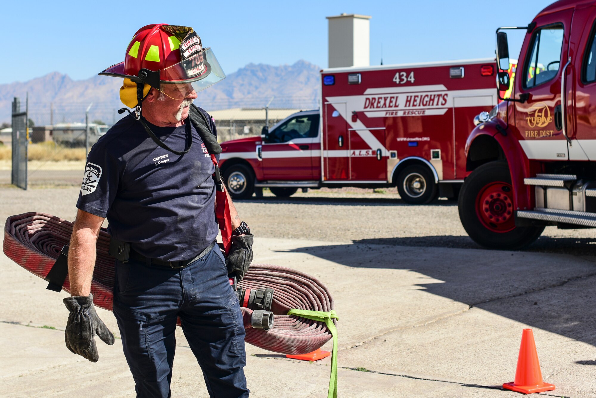 A photo of a firefighter carrying a hose.