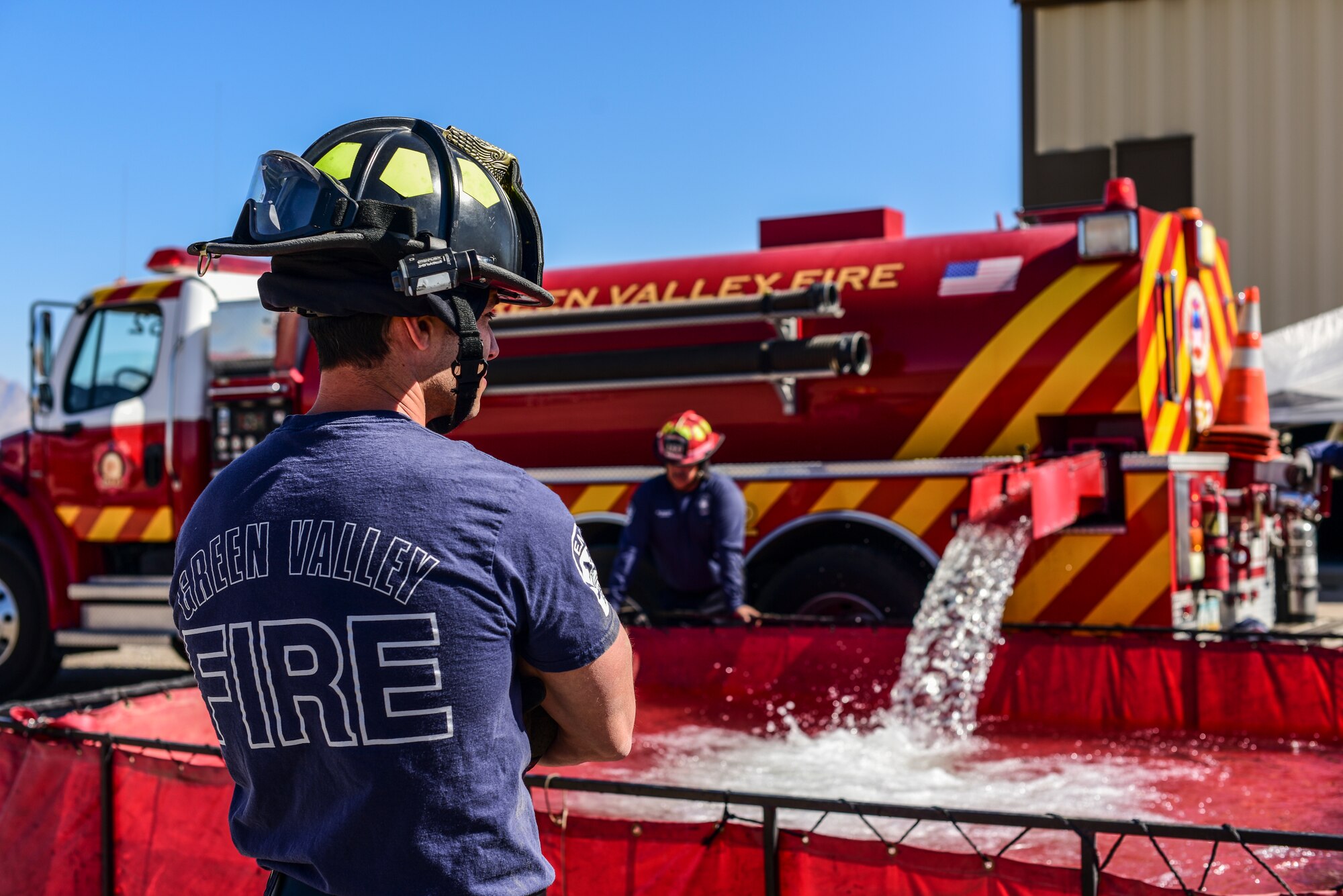 A photo of a firefighter filling a portable water tank.