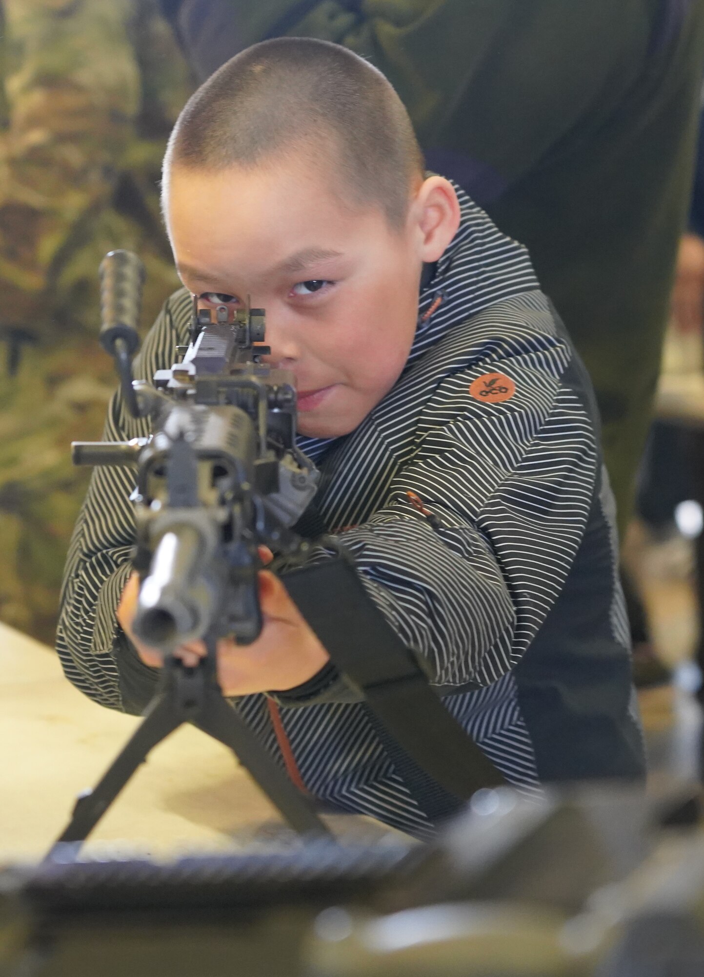A child looking down the sight of a rifle on display