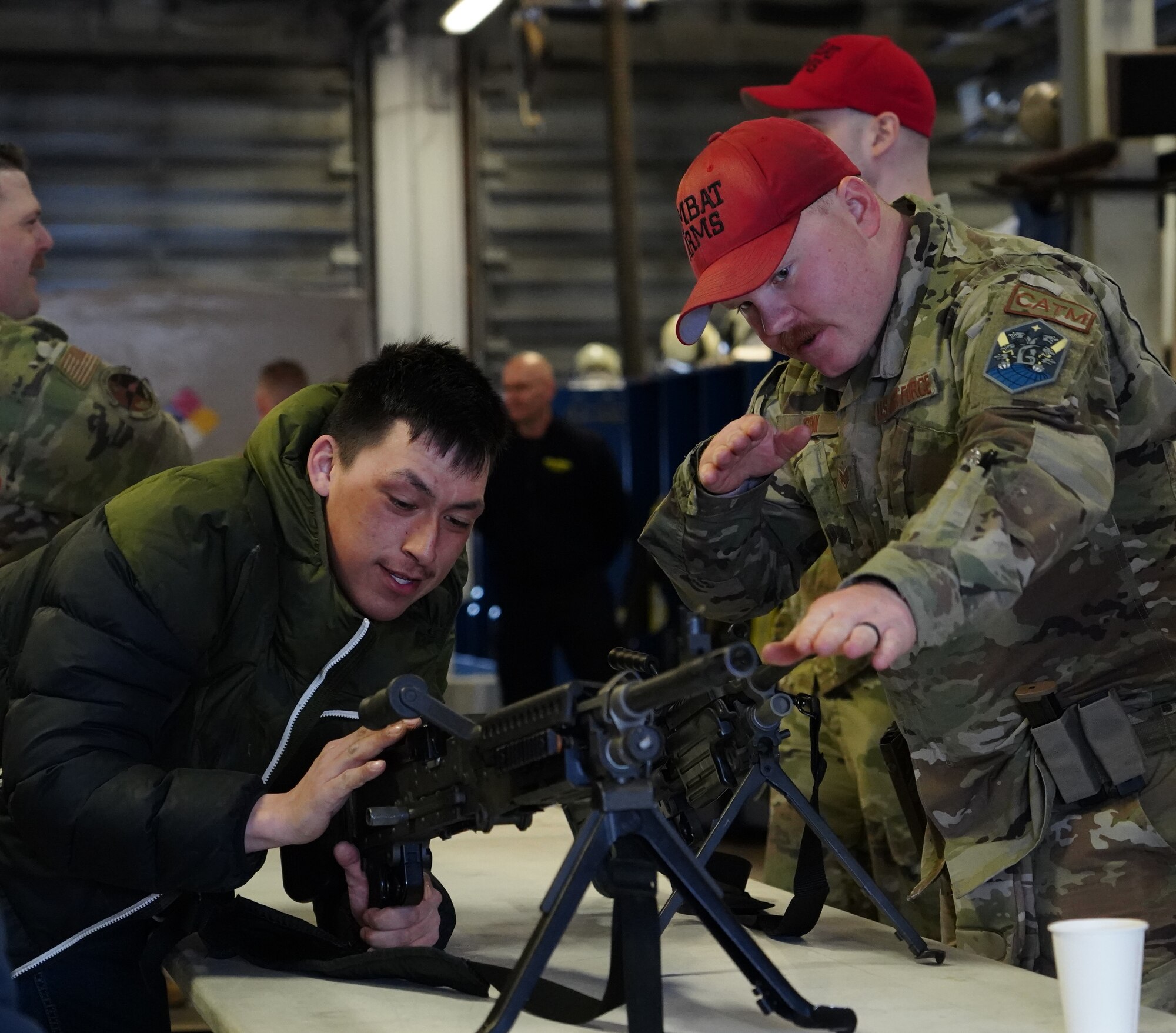 An airman showing a Greenland local a rifle on display