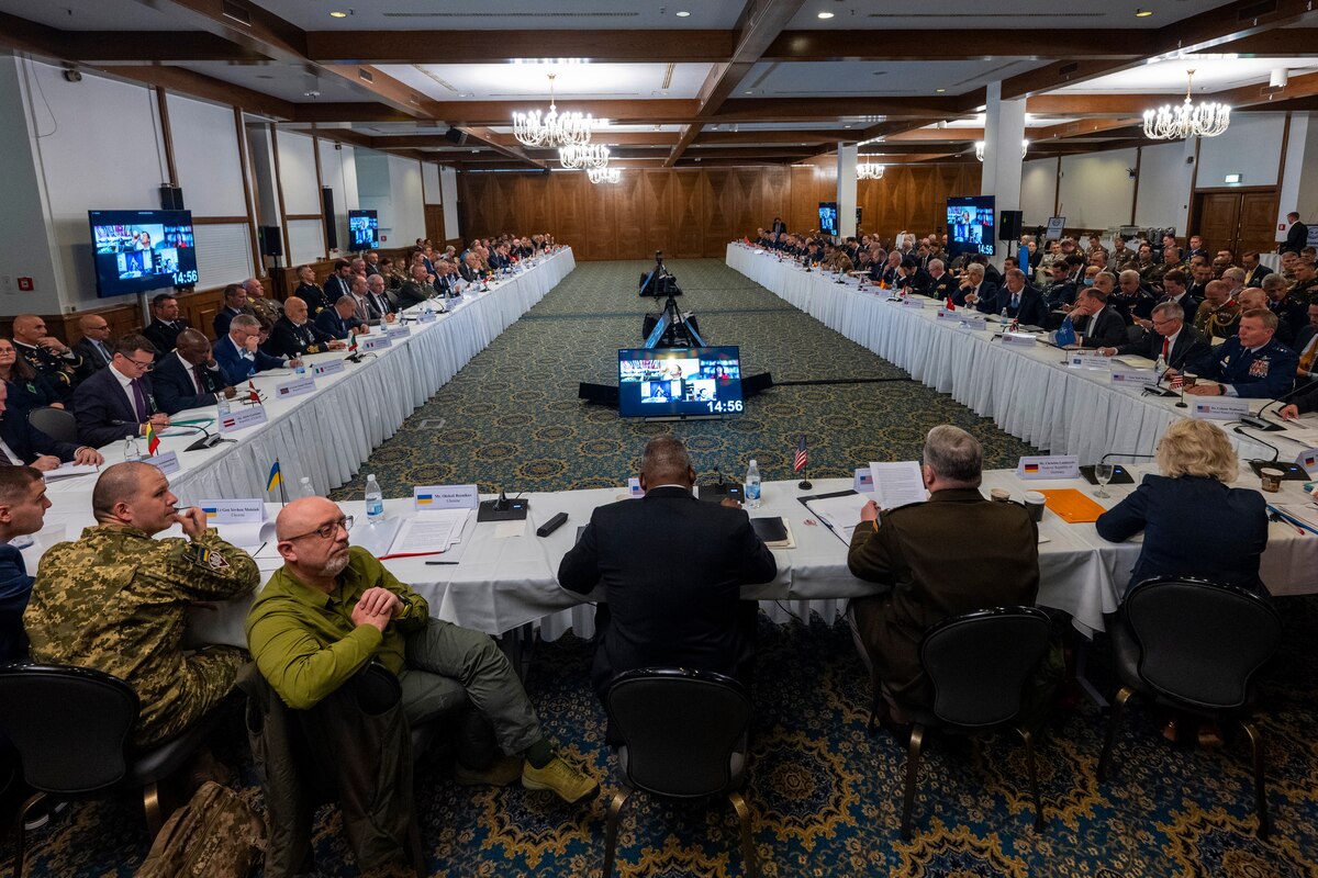 Defense Secretary  Lloyd J. Austin III sits at the head of tables in a "U" formation with civilian and military officials.