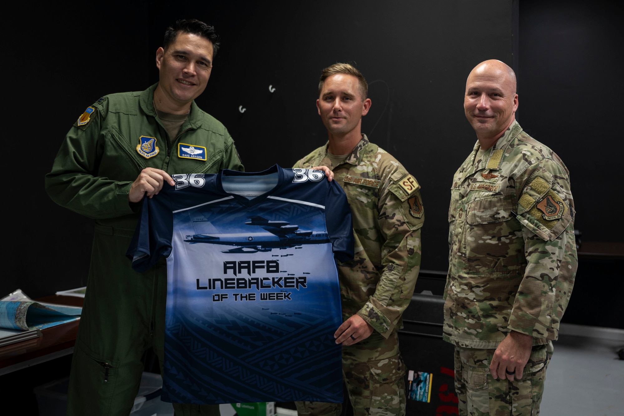 U.S. Air Force Tech. Sgt. David Gwin, a contingency response flight squad leader with the 736th Security Forces Squadron, poses with the Linebacker of the Week jersey with U.S. Air Force Col. David Aragon, 36th Wing vice commander, and U.S. Chief Master Sgt. Brian Smith, 36th Operations Group superintendent, at Andersen Air Force Base, Guam, April 20, 2022.