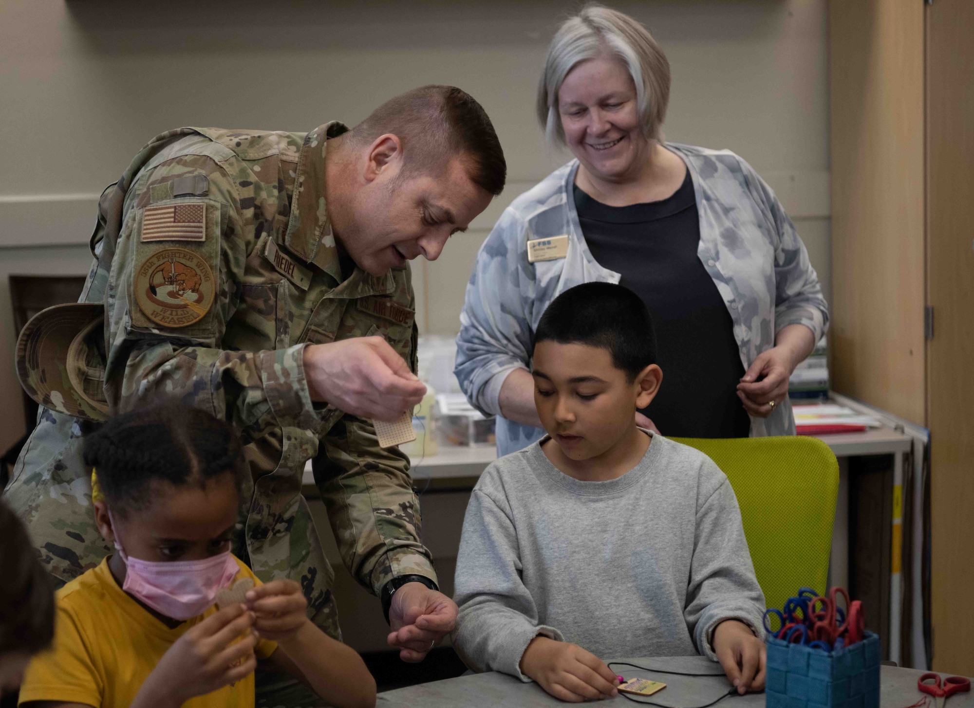A military member helps a child with his craft.