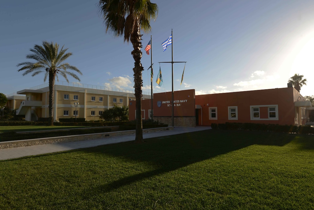 U.S. Naval Support Activity Souda Bay's command building, with the U.S. and Greek flags, and palm trees in front of it. U.S. Naval Support Activity Souda Bay is an operational ashore base in Crete, Greece, that enables U.S., allied and partner nation forces to be where they are needed when they are needed to ensure security and stability in the European, African and Central Command areas of responsibility. U.S. Navy photo by Heather Judkins. 