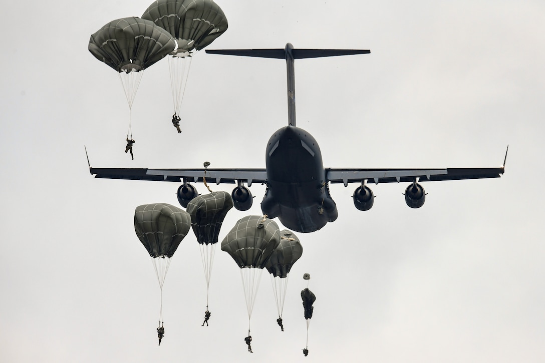 Soldiers with parachutes jump out of a plane during training.