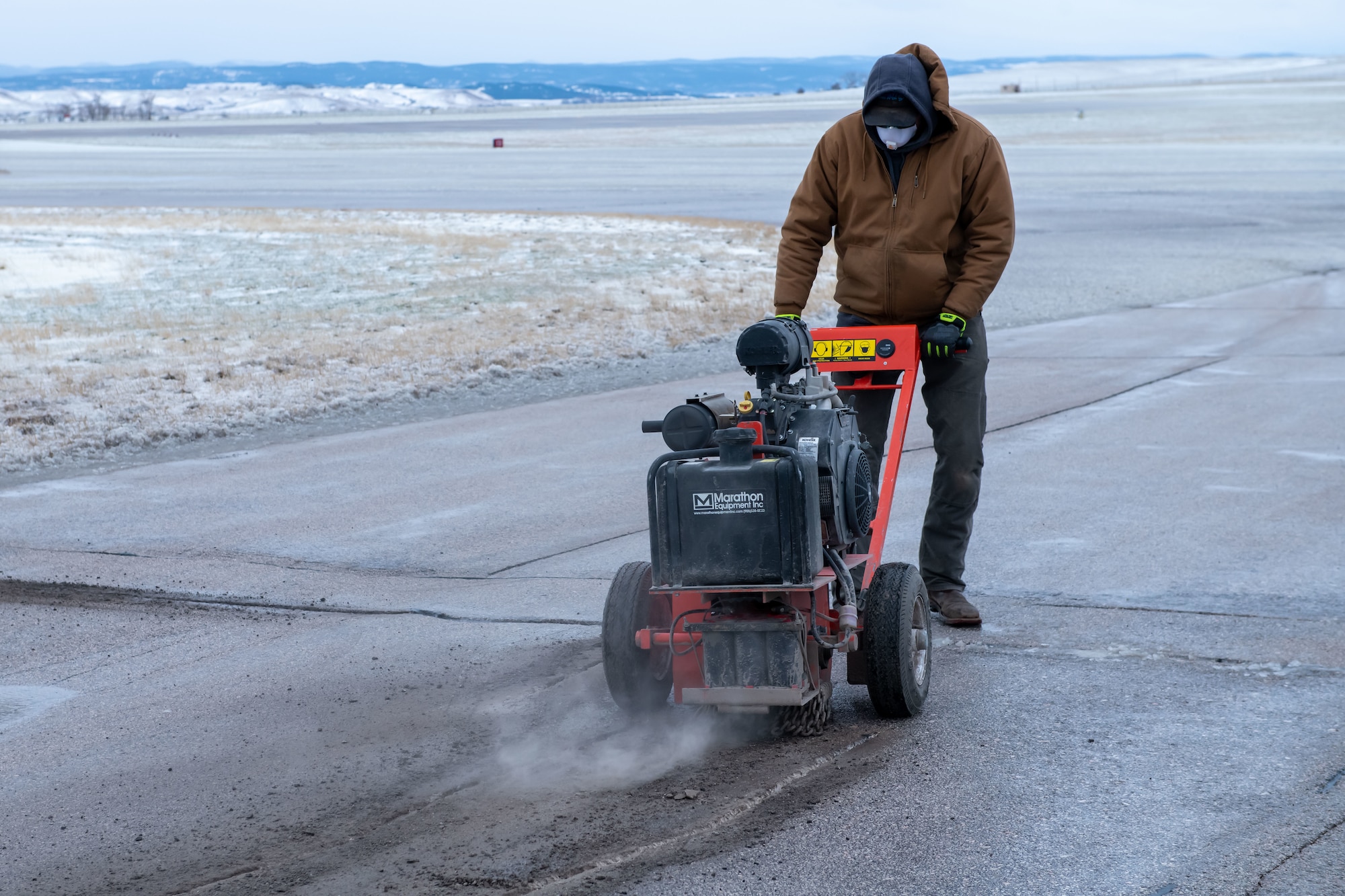 Taylor Bowling, 28th Civil Engineering Squadron heavy equipment operator and pavement repair specialist, uses an asphalt saw to enlarge a crack in the flight line on Ellsworth Air Force Base, S.D., April 24, 2022. In order for certain cracks to be repaired, they must first be enlarged before the appropriate sealant can be used to fill in the crack. (U.S. Air Force photo by Airman 1st Class Adam Olson)