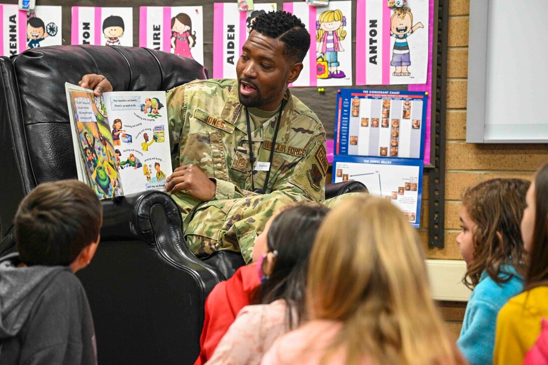 An airman reads a book to children.