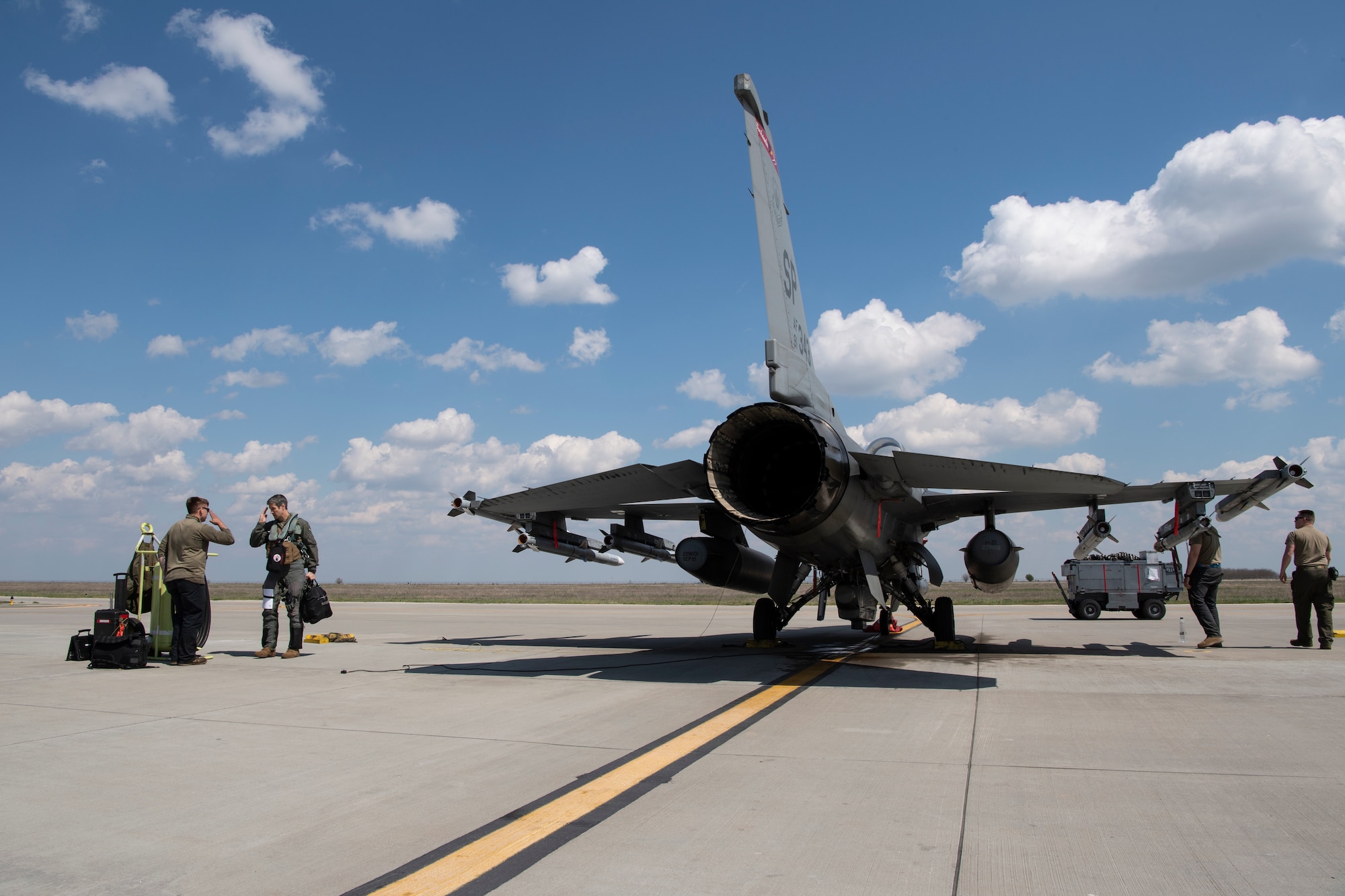 Airmen salute next to an F-16 Fighting Falcon fighter jet.