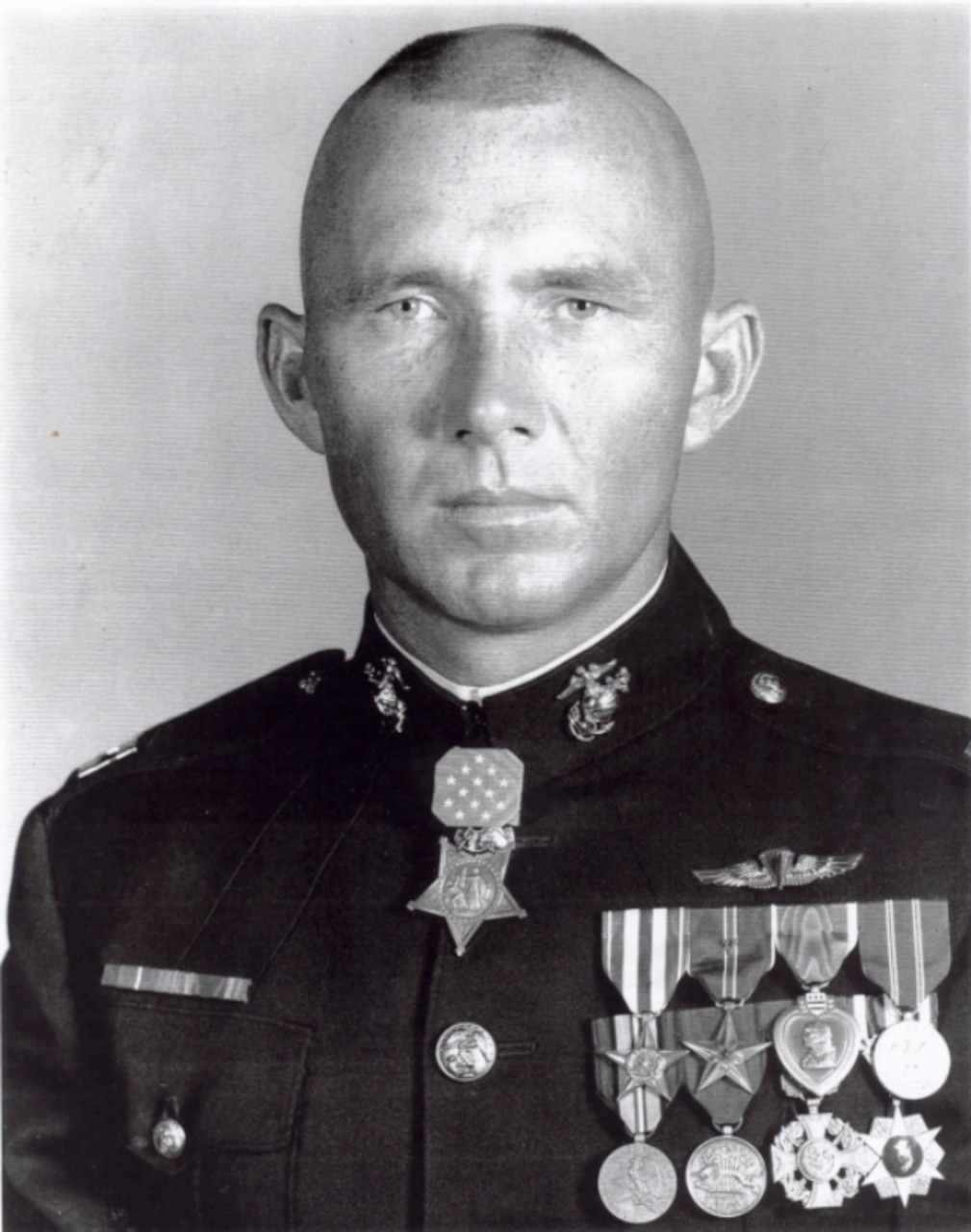 A man wearing a dress uniform and several medals poses for a photo.