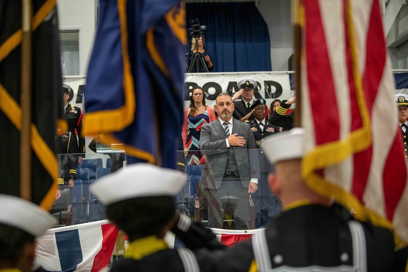 A man places his hand over his heart during a ceremony.