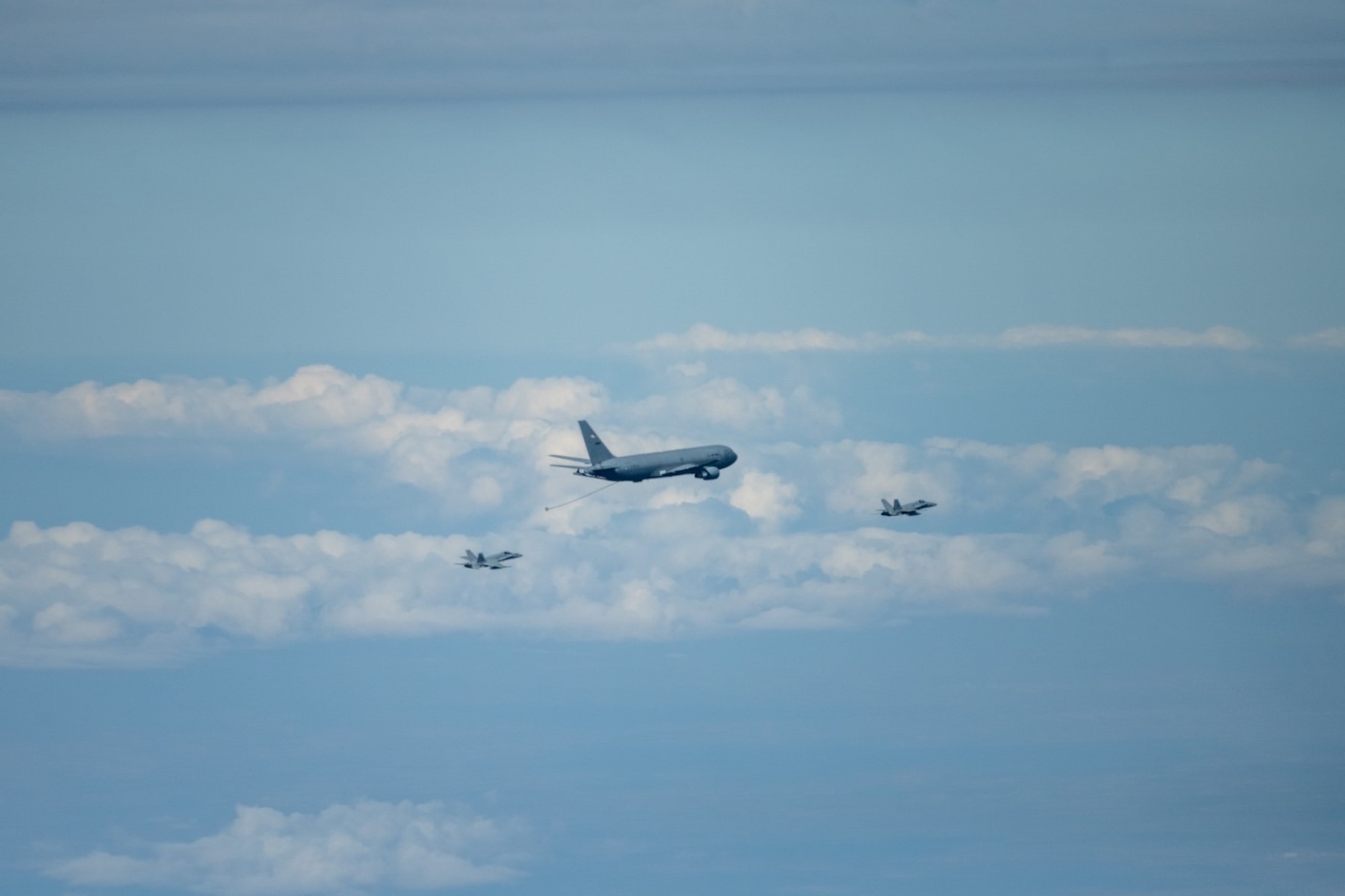 A Spanish Air Force EF-18 Hornet, known as a C-15 in Spain, approaches a U.S. Air Force KC-46A Pegasus for refueling off the aircraft’s centerline drogue April 18, 2022. This fueling method involves trailing a long hose with a windsock called a drogue behind the tanker to refuel certain aircraft types. This mission marked the first refueling of an international receiver for the KC-46A, paving the way for future international operations.(U.S. Air Force photo by Staff Sgt. Nathan Eckert)