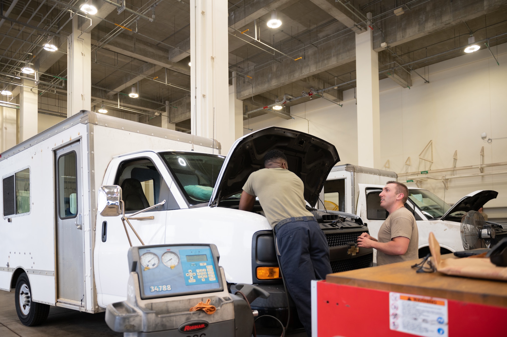 Airman performing maintenance on a vehicle and talking