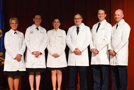 Rear Adm. Cynthia A. Kuehner, commander of Naval Medical Forces Support Command, joins graduates Army Maj. (Dr.) Nicole L. Case, Army Maj. (Dr.) Stephanie S. Hayes, Air Force Maj. (Dr.) Jonathan P. Virnig, and Air Force Capt. (Dr.) Andrew J. Christensen, along with their instructor Air Force Maj. (Dr.) Michael P. Allen, after donning their ‘white coat’ in celebration of graduation from Phase II of the Doctor of Nursing Practice Family Nurse Practitioner training program from the University of Uniformed Services at Joint Base San Antonio – Lackland on April 8, 2022.