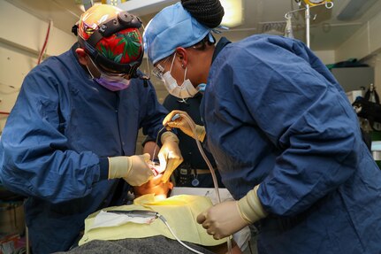 Lt. Cmdr. Bhavin Trivedi, USS Gerald R. Ford’s (CVN 78) oral maxillo facial surgeon, from Raleigh, North Carolina, left, and Hospitalman Malacia Ashford from, Columbia, South Carolina, assigned to Ford’s dental department, perform dental surgery on Culinary Specialist Seaman Asia Sidouang from Modesto, California, assigned to supply department, in Ford’s dental operation room, April 12, 2022. Ford is underway in the Atlantic Ocean conducting carrier qualifications and strike group integration as part of the ship’s tailored basic phase prior to operational deployment. (U.S. Navy photo by Mass Communication Seaman Apprentice Rajah Lee Thornton)