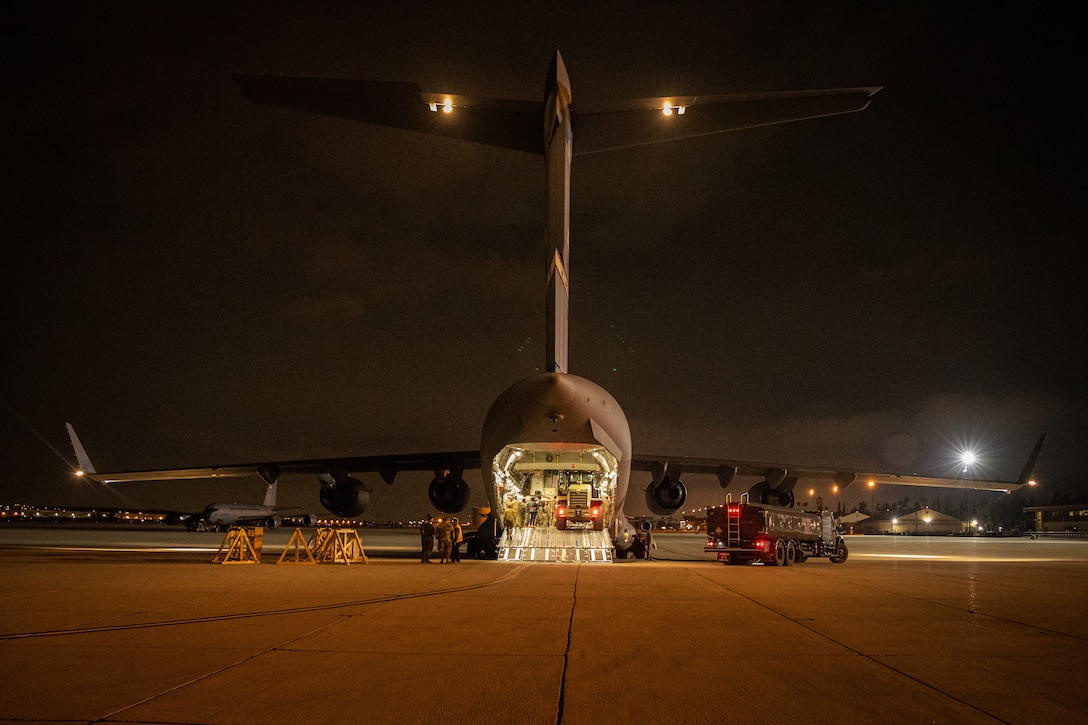 Personnel surround a forklift in the cargo bay of a large aircraft.