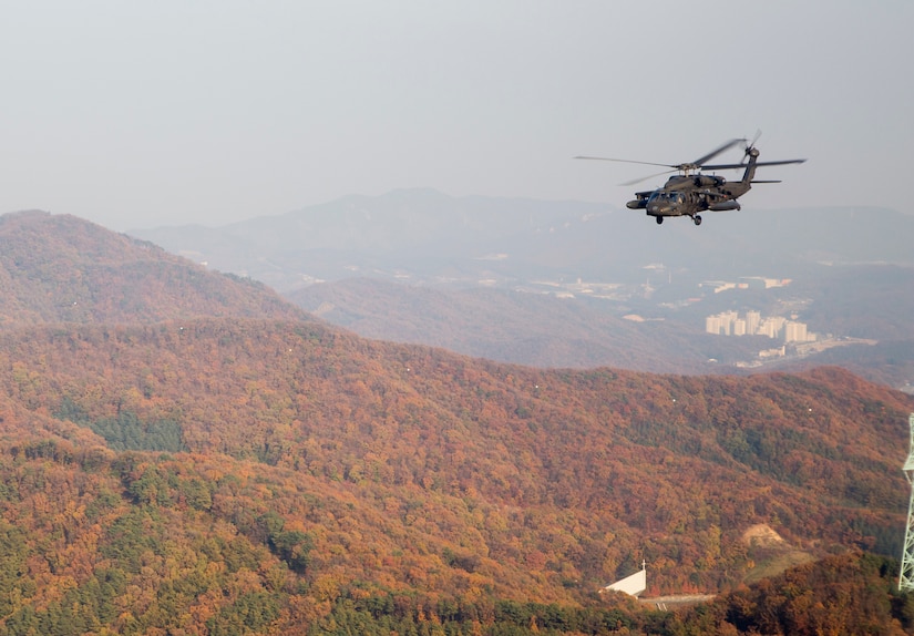 A helicopter flies over mountains in South Korea.