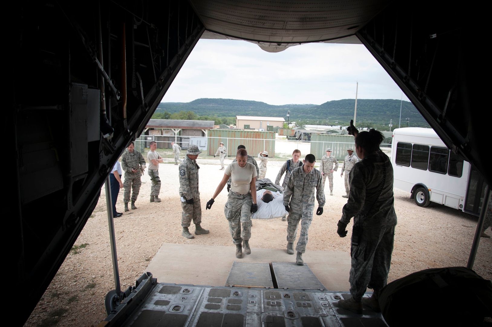 Military personnel carrying a simulated patient into an aircraft.