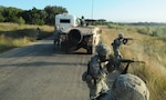 Military members and vehicle on a road.