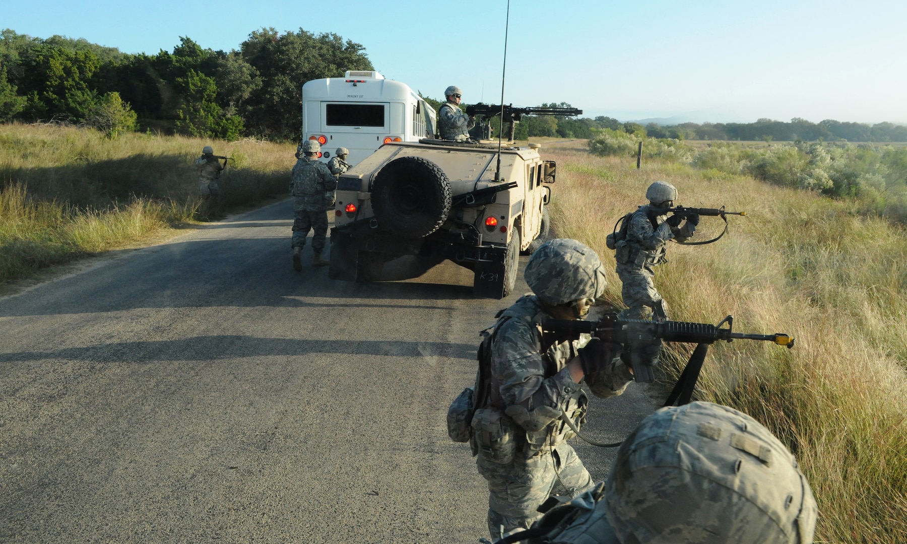 Military members and vehicle on a road.