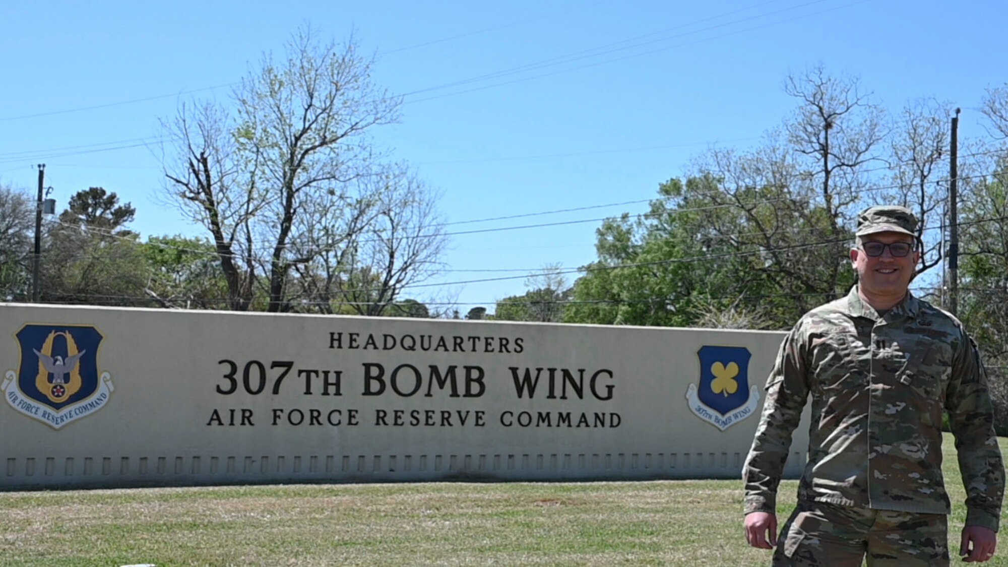 Photo of Airman in front of 307 Bomb Wing sign