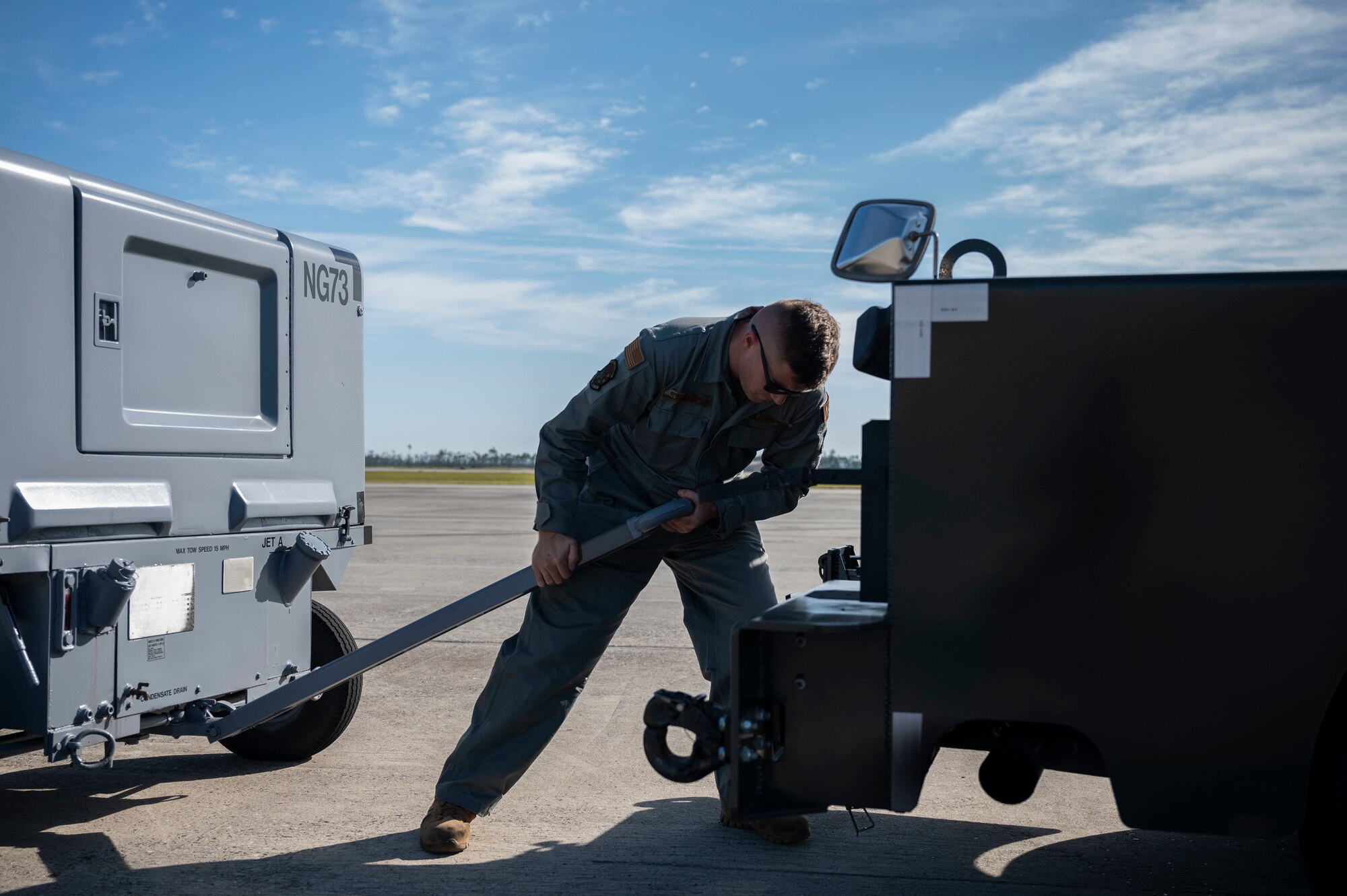 A man connecting a generator to the tow-hitch of a truck