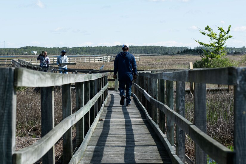 An individual walks down a boardwalk.