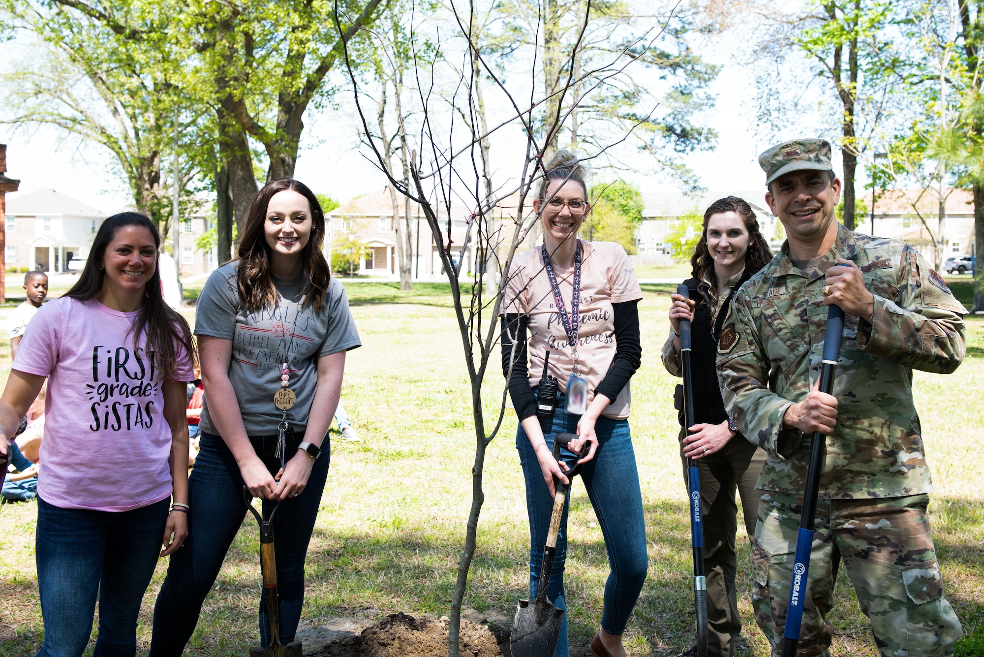 Individuals gather around a newly planted tree.