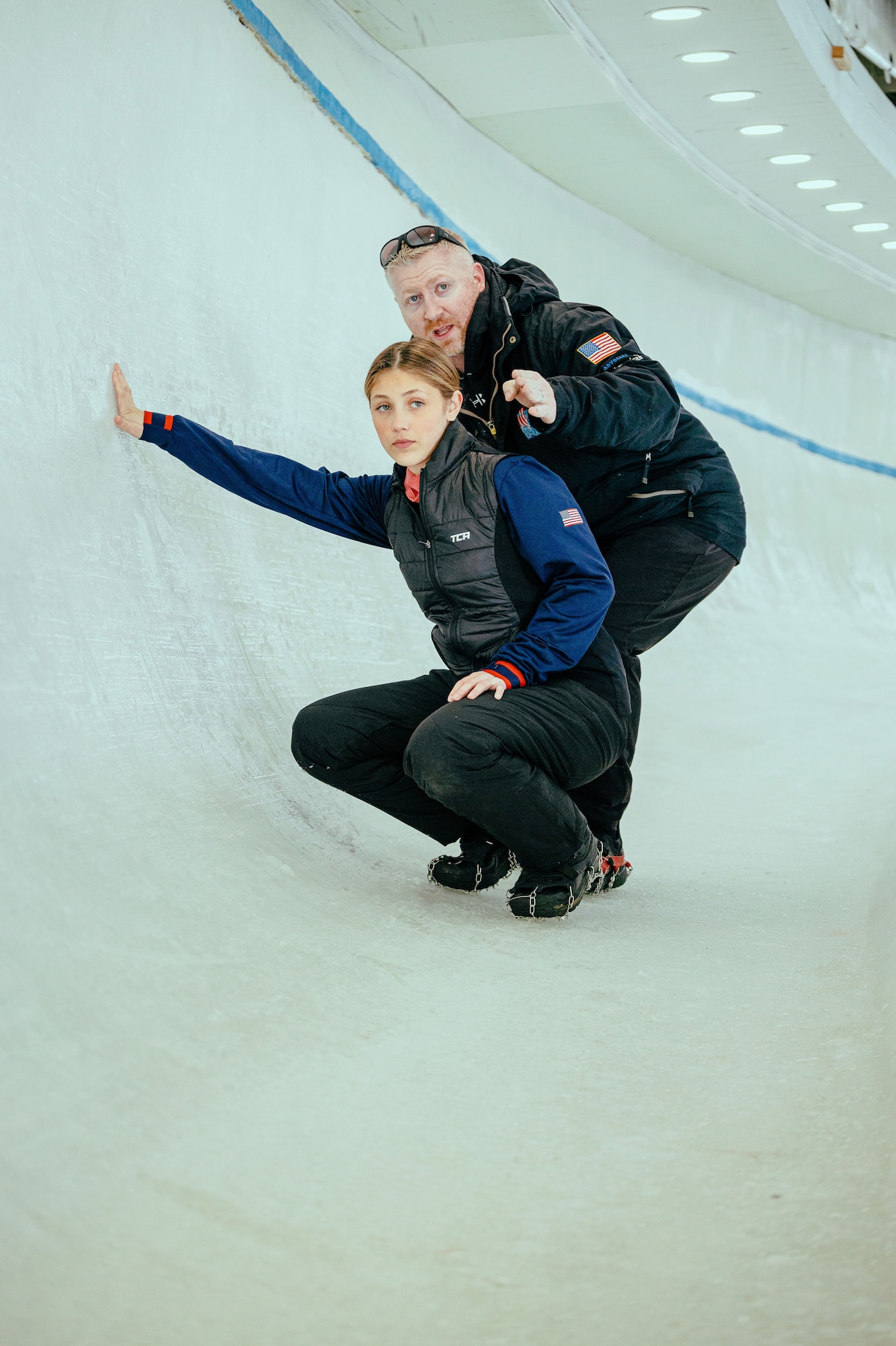 Emily Bradley is taking in some bobsledding coaching from her father. He has years of experience to share with his daughter. They are looking down range inside the track before a run.