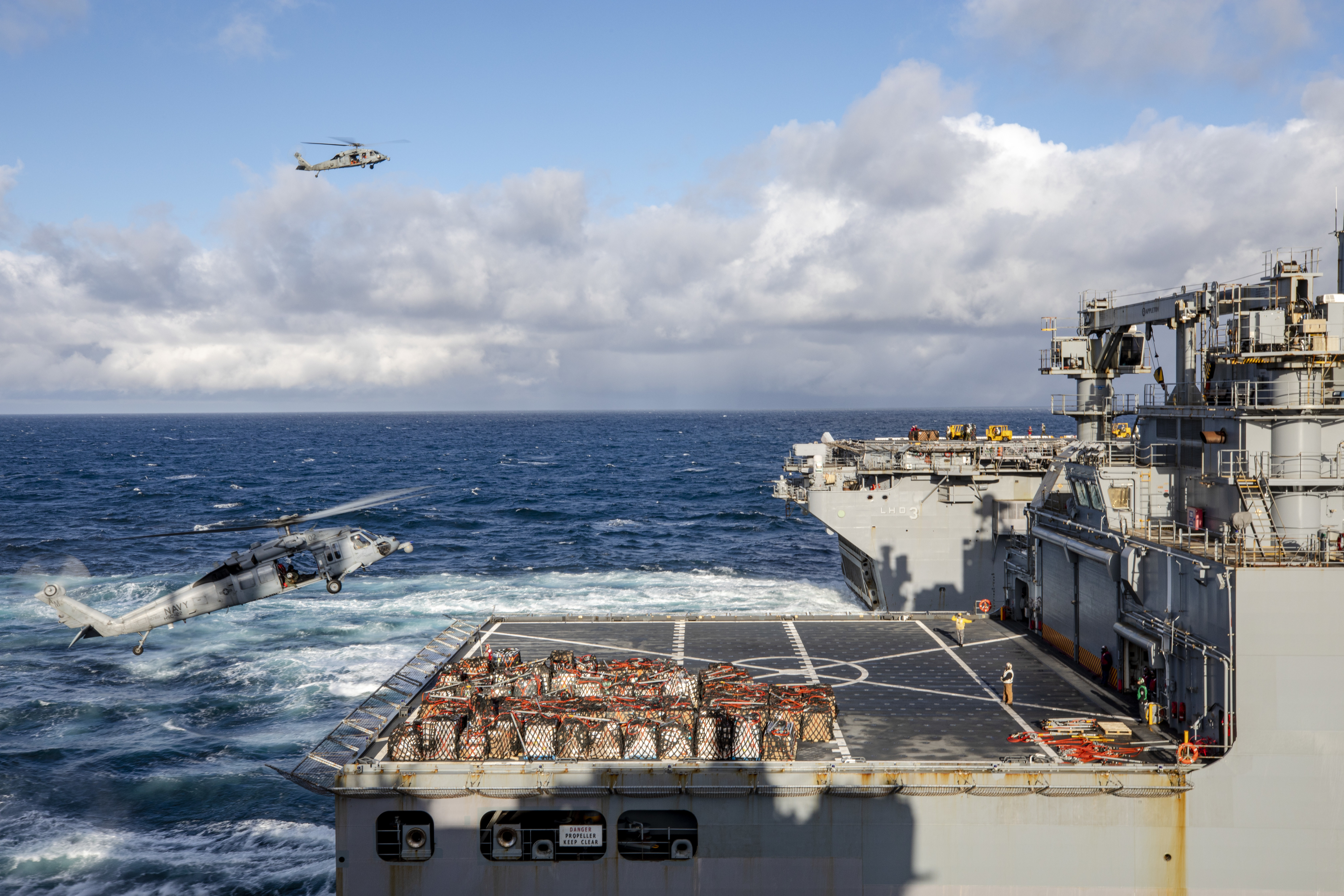 MH-60 Sea Hawks fly packages from the Lewis and Clark-class dry cargo ship USNS Robert E. Peary (T-AKE-5), closest, to USS Kearsarge (LHD-3), during a vertical replenishment, April 25, 2022.