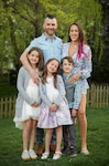 Karen barker poses standing with her husband and three young children.