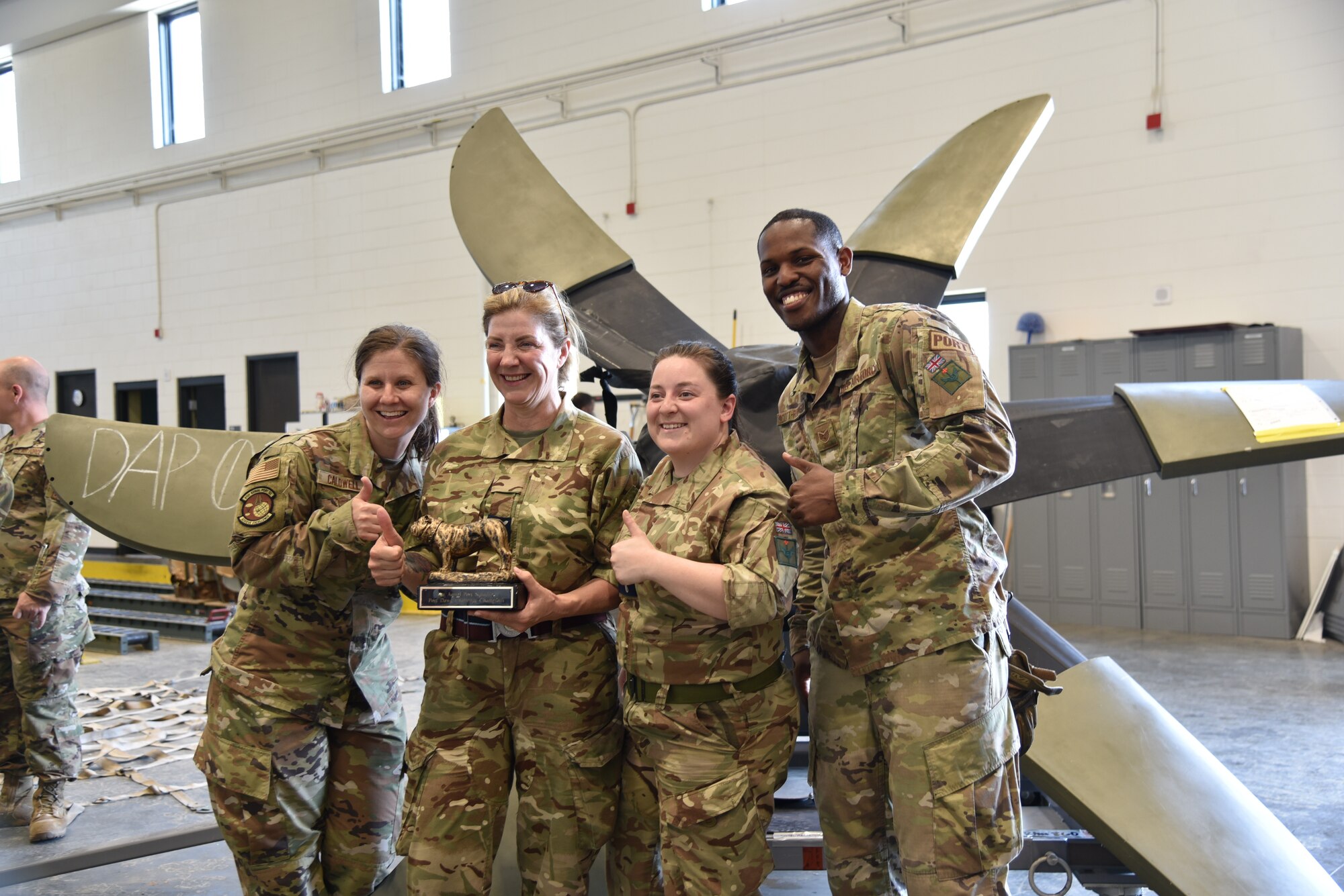 Two U.S. Air Force Reserve (outside) and two British Royal Air Force Reserve member (inside) hold the Port Dawg trophy after winning the mini Port Dawg competition and pose for a photo.