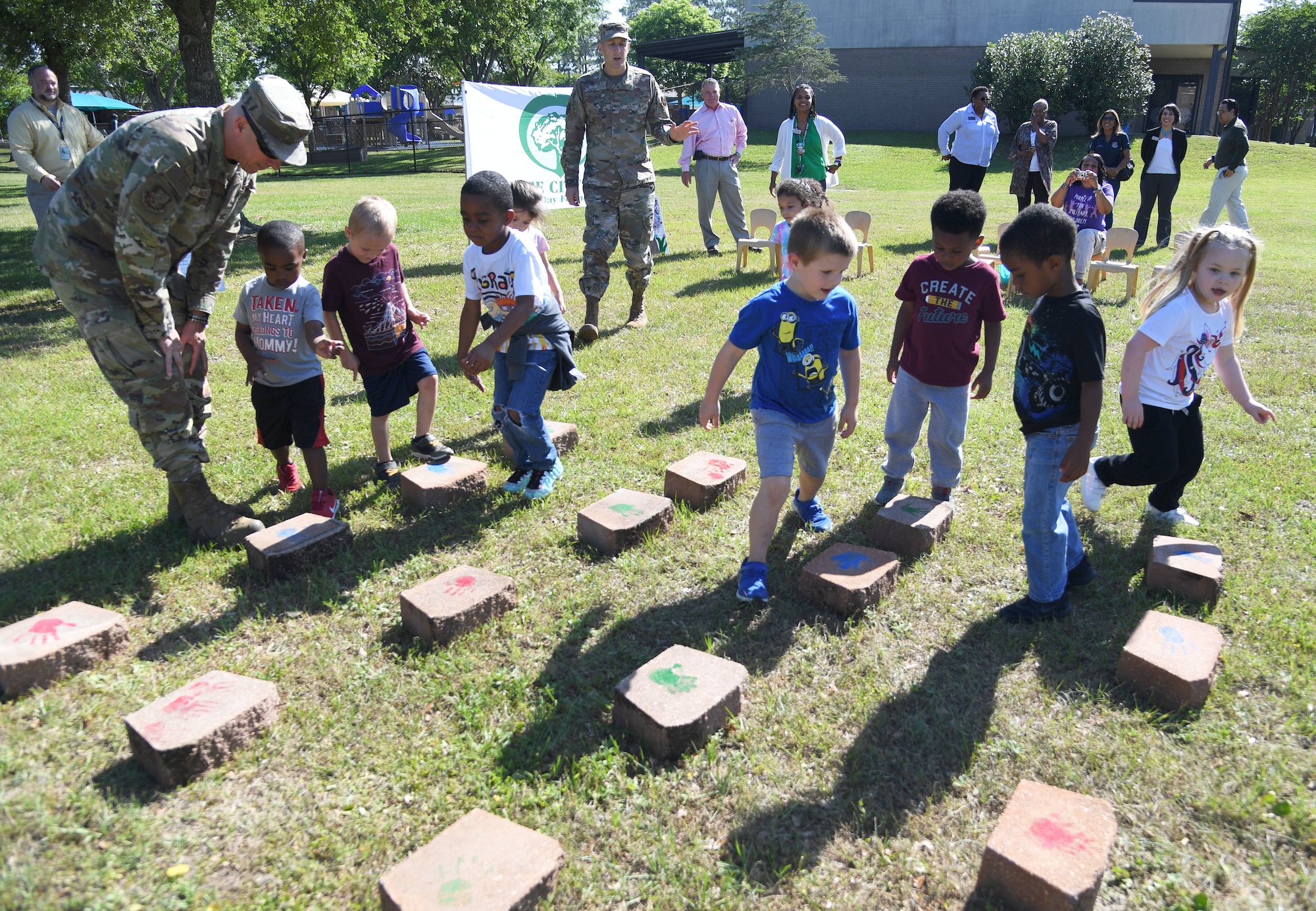 U.S. Air Force Col. William Hunter, 81st Training Wing commander, and children from the Keesler Child Development Center view hand painted stones they made for the Arbor Day Celebration at Keesler Air Force Base, Mississippi, April 28, 2022. A tree planting ceremony and a Tree City USA flag presentation also took place at the event. (U.S. Air Force photo by Kemberly Groue)