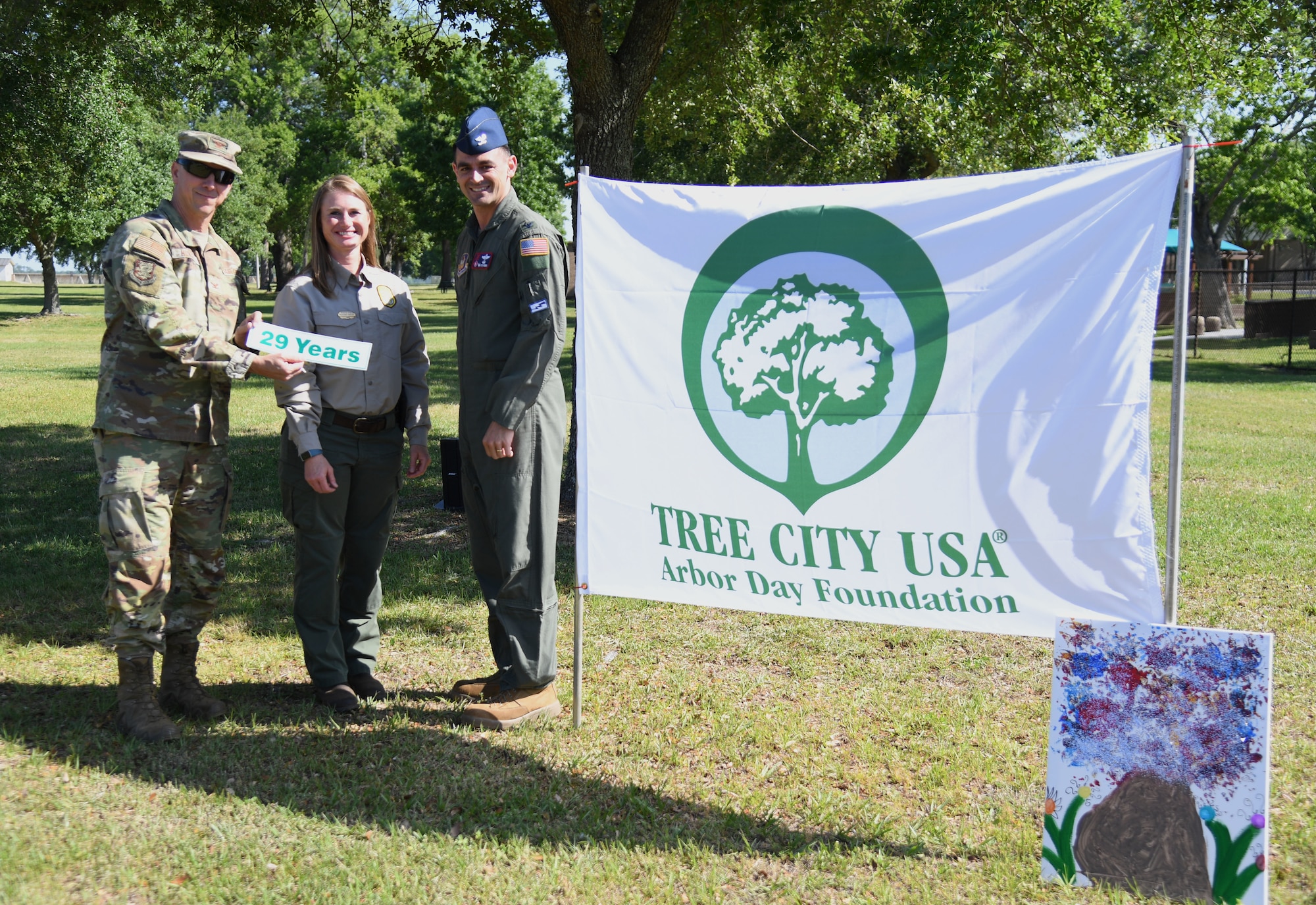 U.S. Air Force Col. William Hunter, 81st Training Wing commander, Meacham Harlow, Urban & Community Forestry Partnership coordinator, and Col. Stuart Rubio, 403rd Wing commander, pose for a photo with the Tree City USA flag during the Arbor Day Celebration outside of the child development center at Keesler Air Force Base, Mississippi, April 28, 2022. A tree planting ceremony also took place at the event. (U.S. Air Force photo by Kemberly Groue)