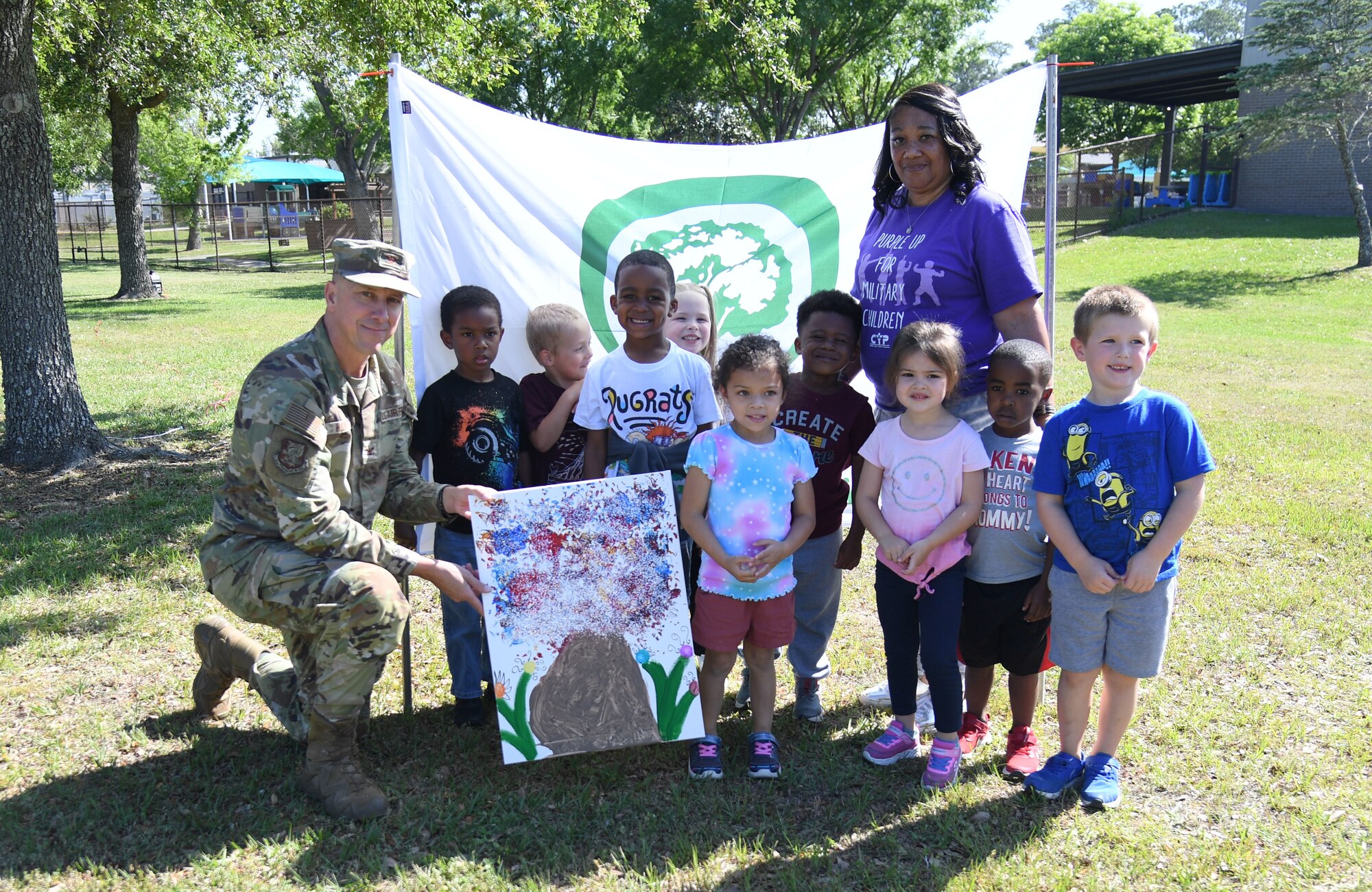 U.S. Air Force Col. William Hunter, 81st Training Wing commander, and children from the Keesler Child Development Center pose for a photo with a painting they made during the Arbor Day Celebration at Keesler Air Force Base, Mississippi, April 28, 2022. A tree planting ceremony and a Tree City USA flag presentation also took place at the event. (U.S. Air Force photo by Kemberly Groue)