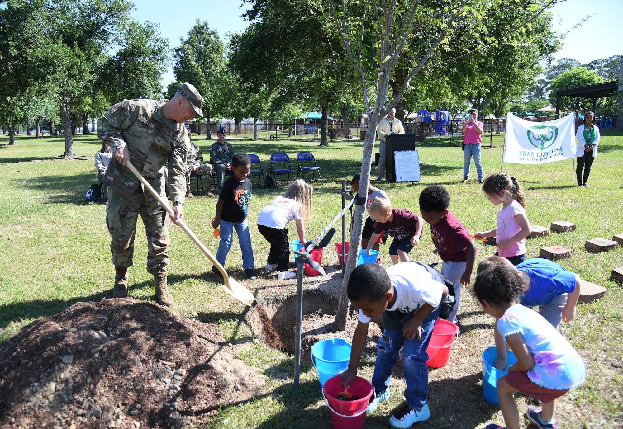 U.S. Air Force Col. William Hunter, 81st Training Wing commander, and children from the Keesler Child Development Center participate in a tree planting ceremony during the Arbor Day Celebration at Keesler Air Force Base, Mississippi, April 28, 2022. A Tree City USA flag presentation also took place at the event. (U.S. Air Force photo by Kemberly Groue)