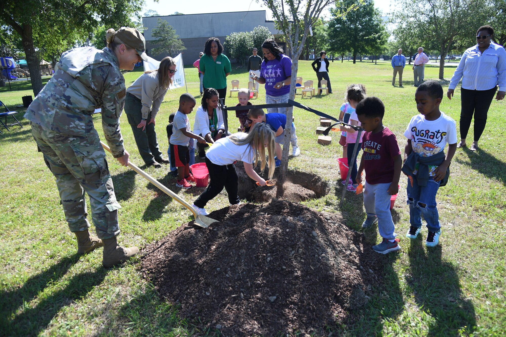 U.S. Air Force Chief Master Sgt. Sarah Esparza, 81st Training Wing command chief, and children from the Keesler Child Development Center participate in a tree planting ceremony during the Arbor Day Celebration at Keesler Air Force Base, Mississippi, April 28, 2022. A Tree City USA flag presentation also took place at the event. (U.S. Air Force photo by Kemberly Groue)